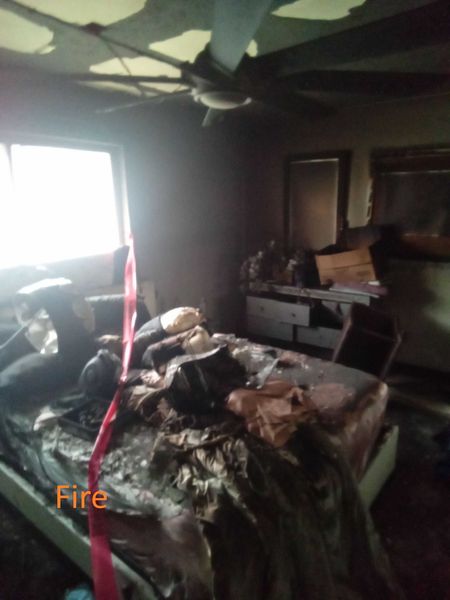 Fire-damaged bedroom with collapsed ceiling burned bed and soot throughout